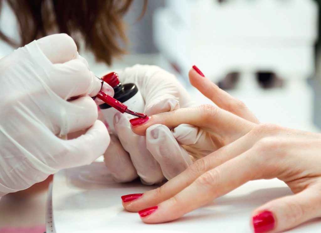 Close-up of young woman doing manicure in salon. Beauty concept.